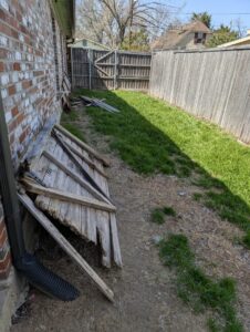 A damaged wooden fence section needing repair or replacement, a service provided by Lula - Reinventing Property Maintenance in Overland Park, KS.