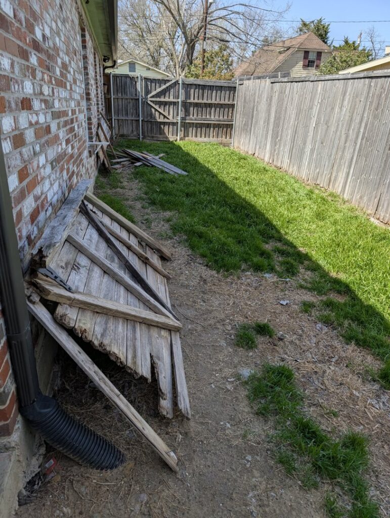 A damaged wooden fence section needing repair or replacement, a service provided by Lula - Reinventing Property Maintenance in Overland Park, KS.