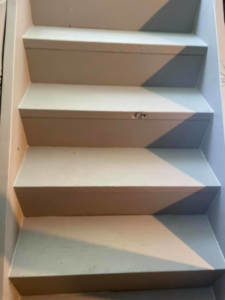 Damaged wooden stairs showing a chip on a tread, a common handyman repair job by MS Carpets in Reynoldsburg, OH.