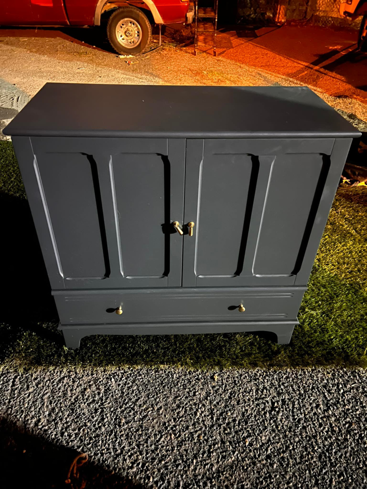 A dark blue wooden cabinet placed outdoors, ready for general junk removal by Junk2Dump in Sacramento, CA.