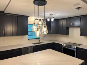 A stylish kitchen remodel featuring dark blue cabinets and modern pendant lighting by Beyond Builders in Tampa, FL