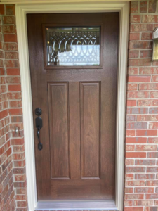 A newly installed dark brown front door with decorative glass on a brick house by The Window & Door Gallery in Elizabethtown, KY.
