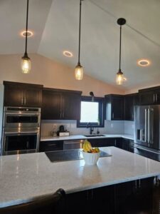 A modern kitchen remodel featuring dark cabinets, a central island, and stylish pendant lights by Boisen Remodeling LLC in Appleton, WI.