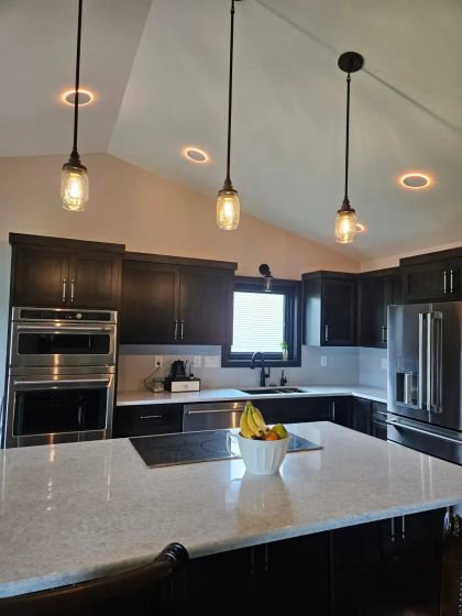 A modern kitchen remodel featuring dark cabinets, a central island, and stylish pendant lights by Boisen Remodeling LLC in Appleton, WI.