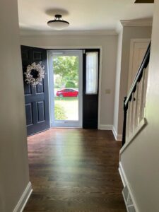 An elegant entryway with dark hardwood flooring and a black front door, completed by Nelson Hardwood Flooring in Madison, WI.