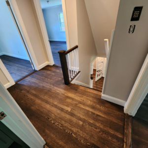 A newly installed dark hardwood floor in a hallway and staircase area by floorzone.inc in Los Angeles, CA.