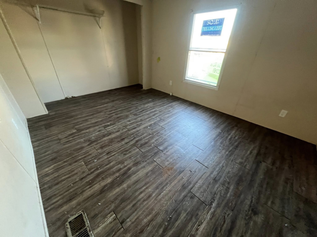 A room with new dark laminate flooring installed, ready for occupancy, completed by Cosa Cleanouts & Junk Removal in Topeka, KS.