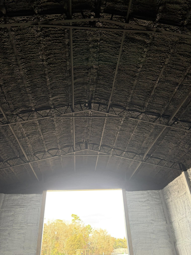 A close-up view of a ceiling covered with dark spray foam insulation installed by Gulf Coast Spray Foam Insulation & Coatings, LLC in Mobile, AL