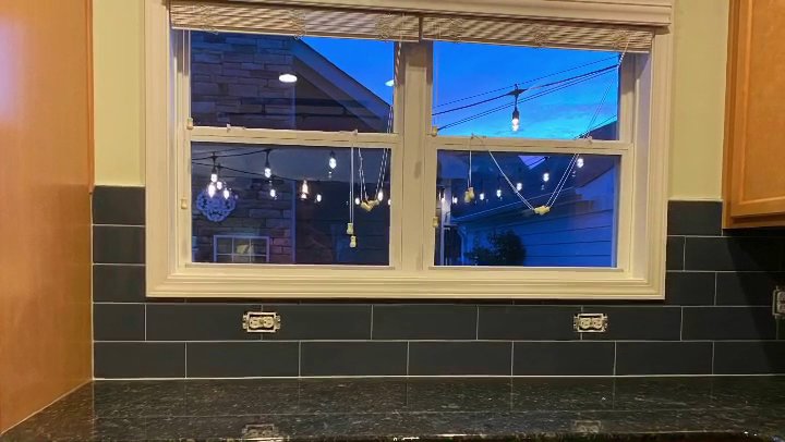 A newly installed dark subway tile kitchen backsplash with electrical outlets by Goubar Tile And More in Raleigh, NC.
