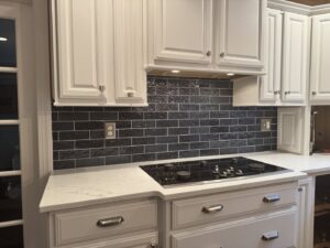 A newly installed dark subway tile kitchen backsplash above a stovetop, completed by Tile Jawn in Philadelphia, PA.