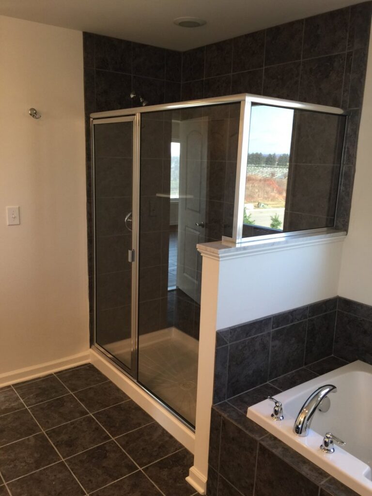 A sophisticated bathroom renovation with dark tiled shower and adjacent tub installation by Lehigh Shower Glass in Bethlehem, PA