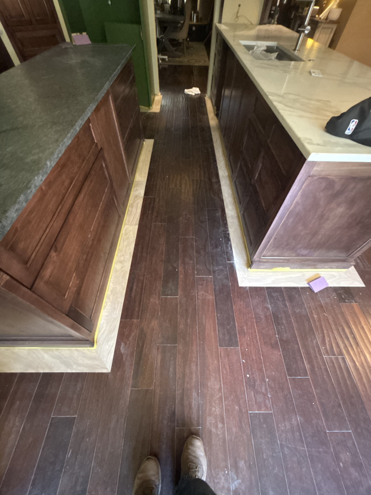 Dark wood flooring and base trim around kitchen islands during renovation by New Era Painting & Construction, Jefferson, NC.