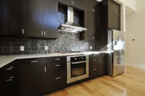 A dark wood kitchen remodel with white countertops and subway tile backsplash by Stone Age Granite of Austin, TX.