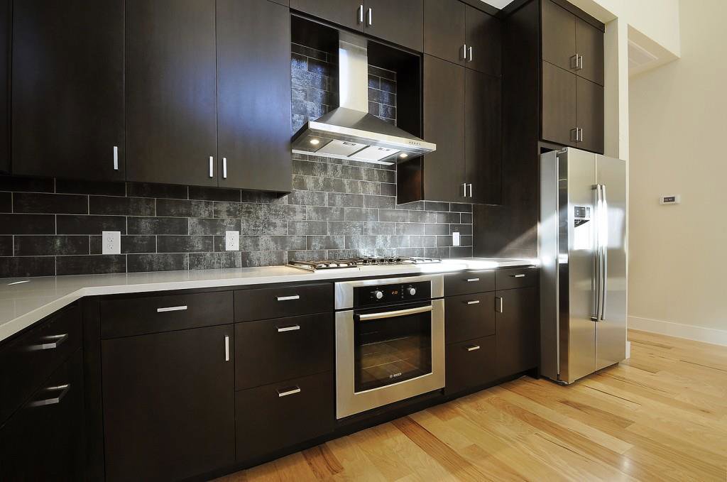 A dark wood kitchen remodel with white countertops and subway tile backsplash by Stone Age Granite of Austin, TX.
