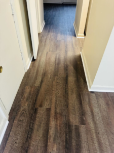 Newly installed dark wood-look laminate flooring in a hallway by NGU Contracting Solutions LLC in Albany, GA.