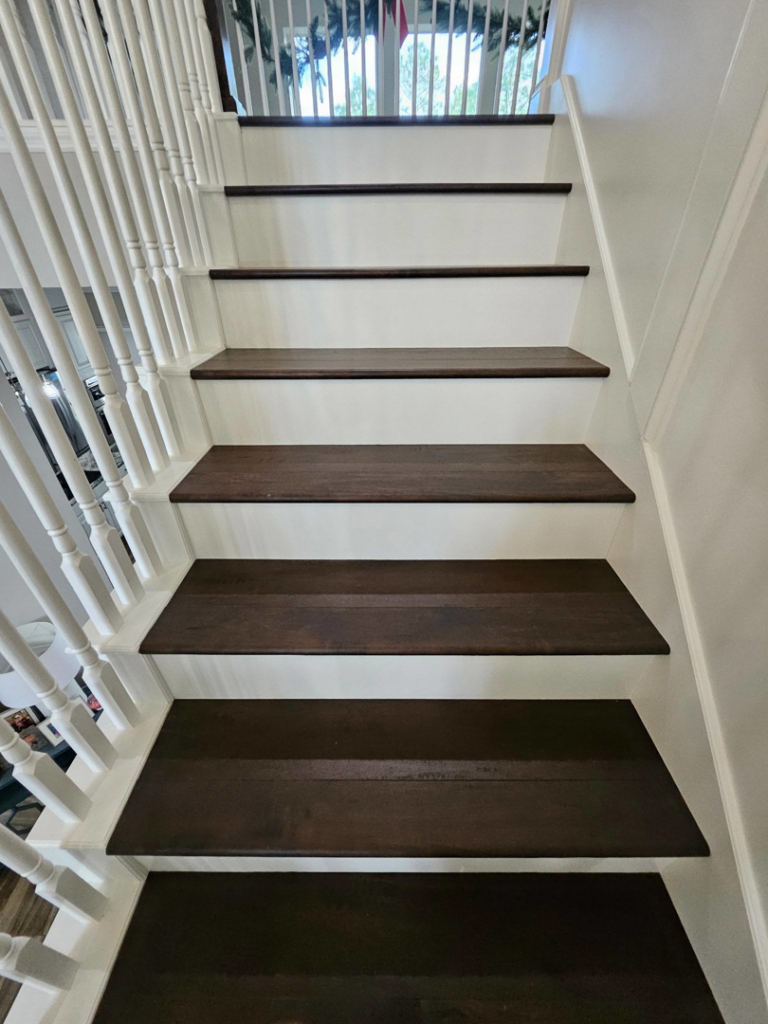 Close-up of newly installed dark wood stair treads and white risers by Amazing Spaces 21 in Orlando, FL
