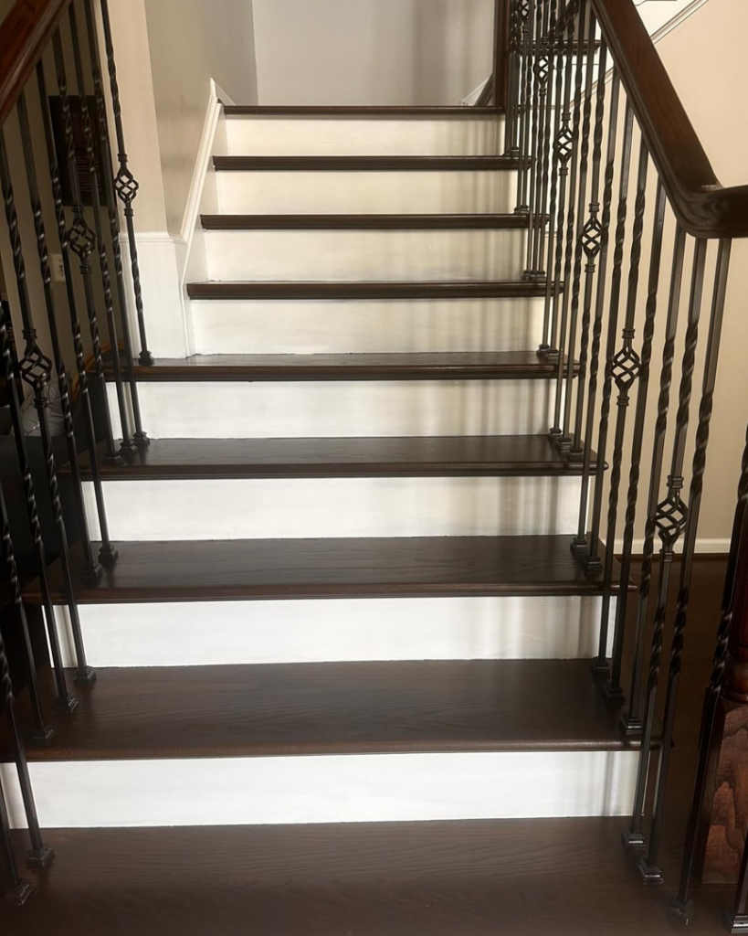 Front view of a beautifully finished dark wood staircase with white risers and wrought iron balusters by International Wood Floors in Gaithersburg, MD