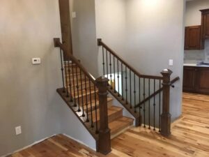 A newly installed dark wood staircase with black metal balusters by Myers & Myers Construction in Spokane, WA.