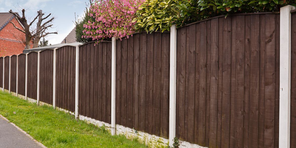 A sturdy dark wooden privacy fence with white concrete posts, installed by R.H. Meyer Fence Co in Cincinnati, OH.