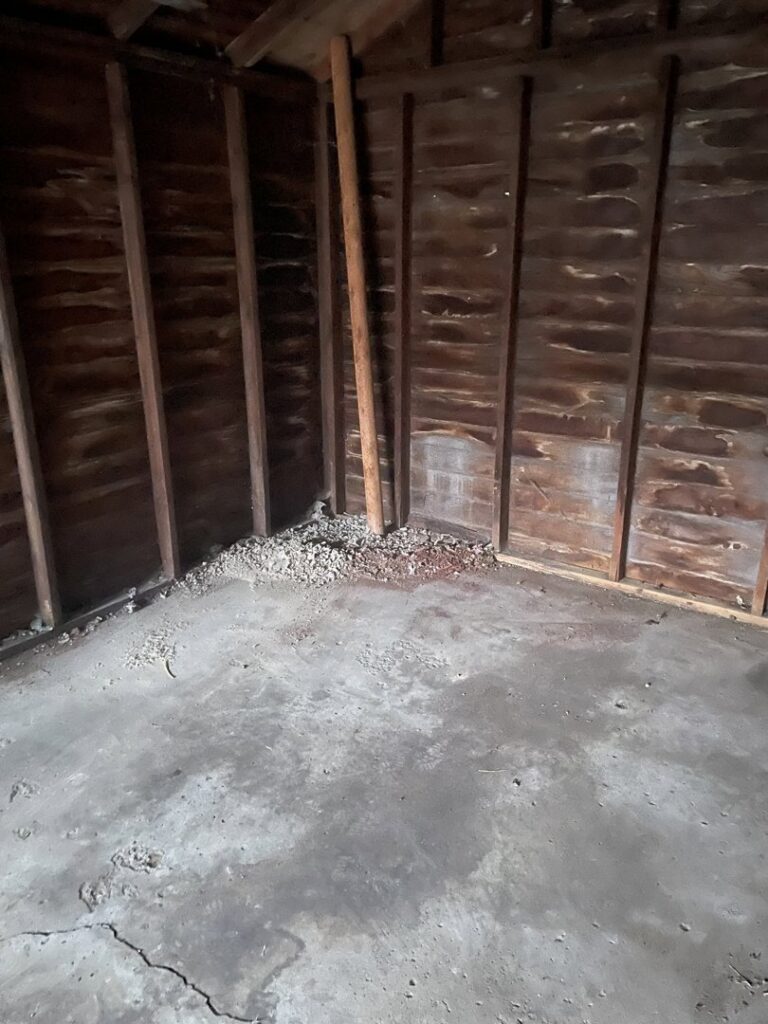 An unfinished room with scattered debris on the concrete floor, awaiting cleanup by Prestige Junk Removal & Hauling in Detroit, MI.