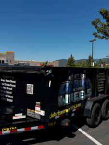 A Debris On Wheels branded black dump trailer, ready for junk removal in Eugene, OR.