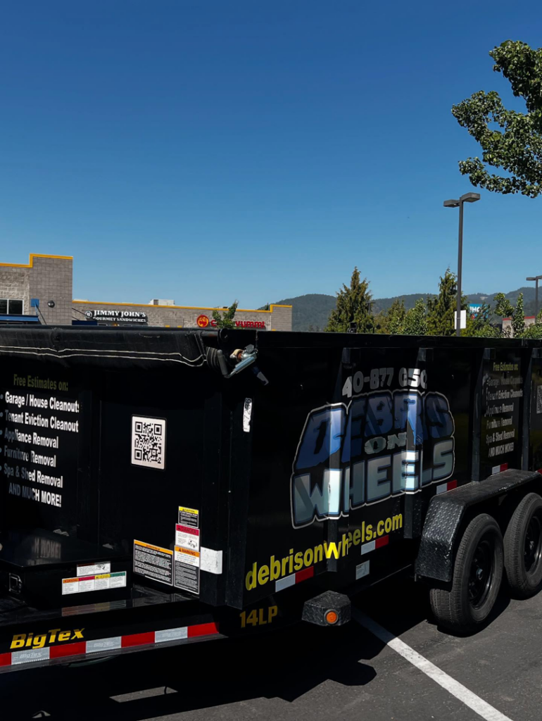 A Debris On Wheels branded black dump trailer, ready for junk removal in Eugene, OR.