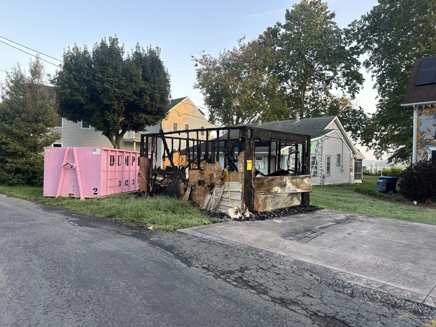 A pink dumpster from Dump It for debris removal next to a burned structure in Middletown, DE