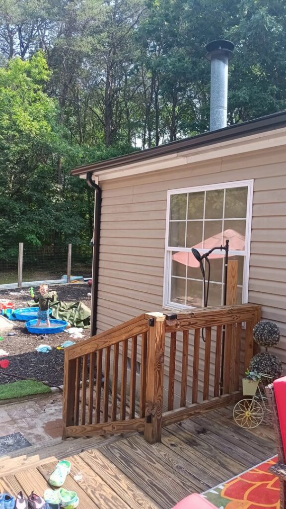 A newly installed wooden deck and railing on the exterior of a home by Shore Home Construction Roofing in Salisbury, MD.
