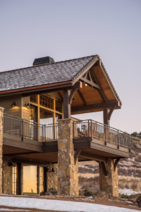 A close-up of a house exterior featuring a deck, stone pillars, and copper gutters by Lee Barker Builder LLC in Fort Collins, CO.