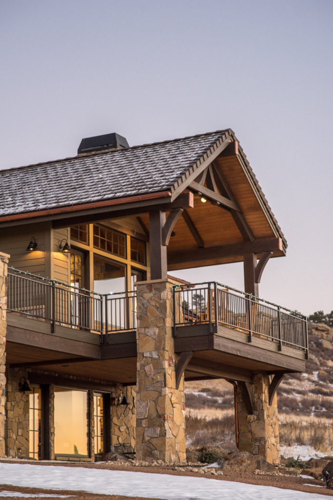A close-up of a house exterior featuring a deck, stone pillars, and copper gutters by Lee Barker Builder LLC in Fort Collins, CO.