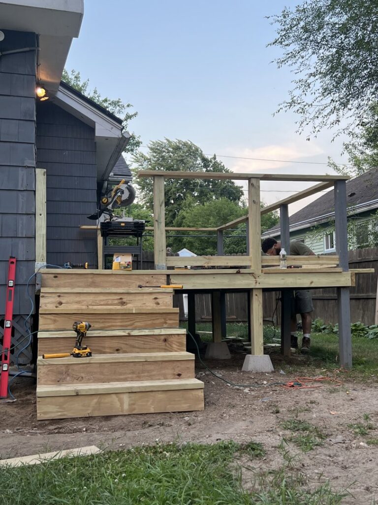 A handyman from TD Estimating Group LLC in Springfield, MA, working on building a new wooden deck and stairs.