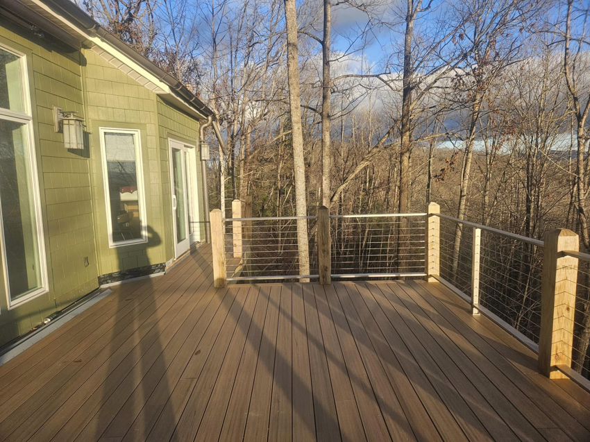 A beautiful deck with cable railing installed next to a green house by American Cable & Rigging in Mills River, NC.