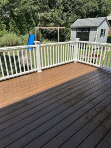 A clean deck with new white railings and a shed in the background by Woodbine Repair & Remodeling in Jamestown, RI.