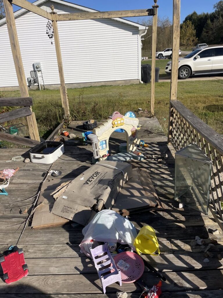 A residential deck cluttered with children's toys, cardboard, and other debris before junk removal by DC'S Removal Service in Neelyville, MO.