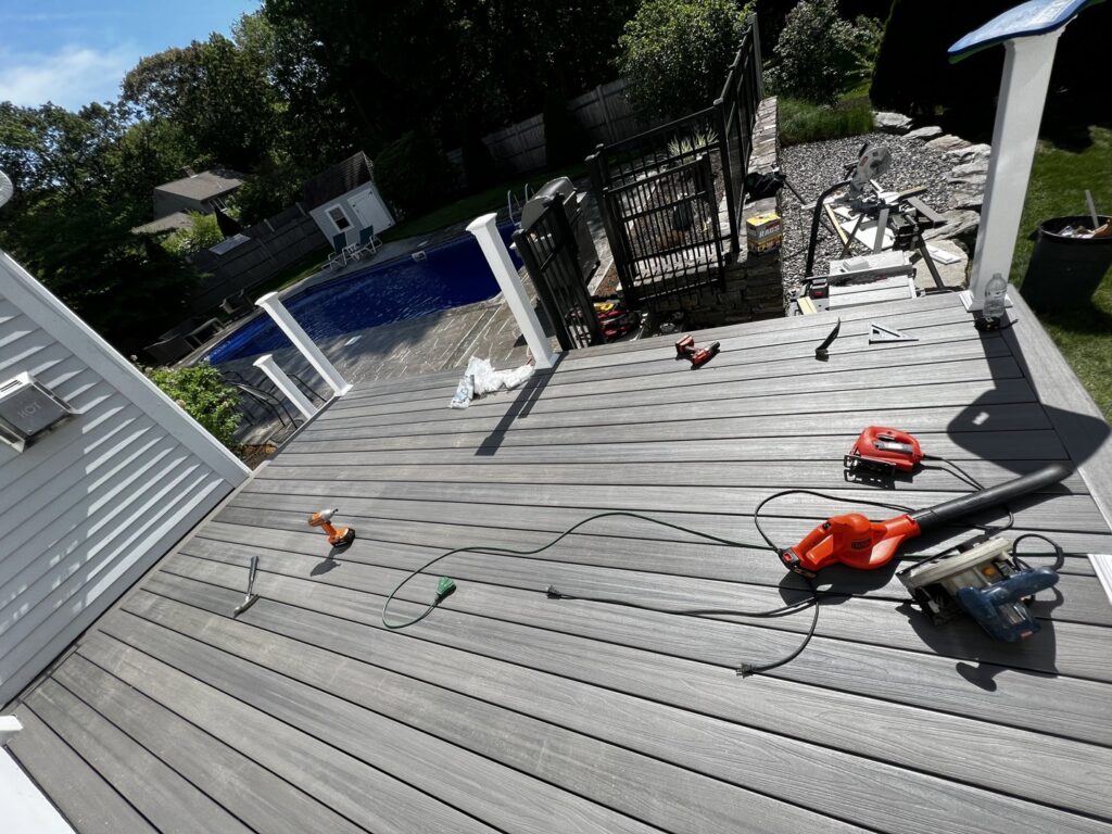 Deck construction in progress with tools on the newly laid composite decking, by Sini's Handyman Services in Falmouth, ME.