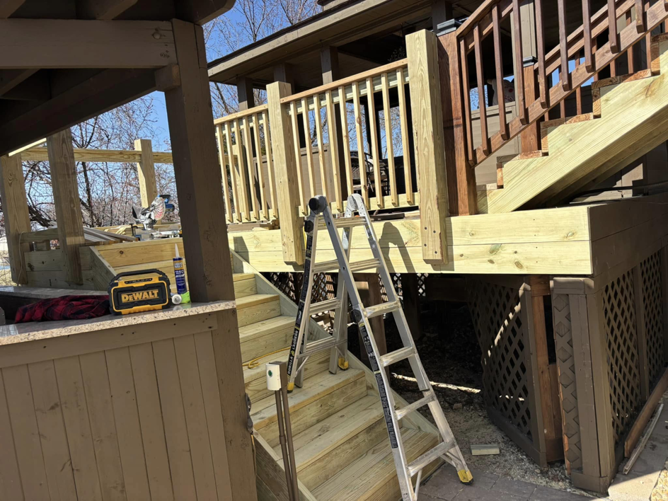 A wooden deck construction project in progress by Top Gunn Family Construction in Truxton, MO, showing new railings and stairs.