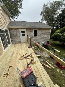A wooden deck under construction or repair, with various tools and lumber, by Woodbine Repair & Remodeling in Jamestown, RI.