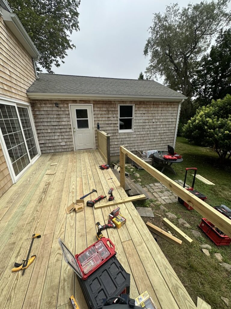 A wooden deck under construction or repair, with various tools and lumber, by Woodbine Repair & Remodeling in Jamestown, RI.