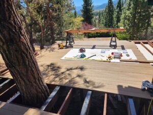 A deck under construction with new composite decking being installed around a tree, a project by Tillman's Handyman Service in Sparks, NV.