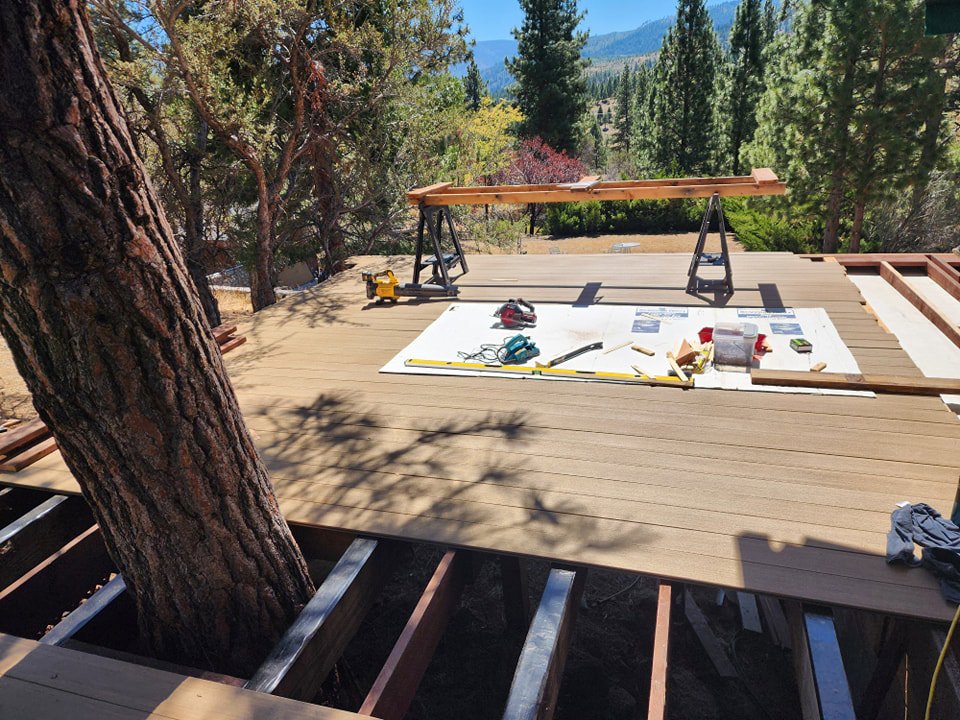 A deck under construction with new composite decking being installed around a tree, a project by Tillman's Handyman Service in Sparks, NV.