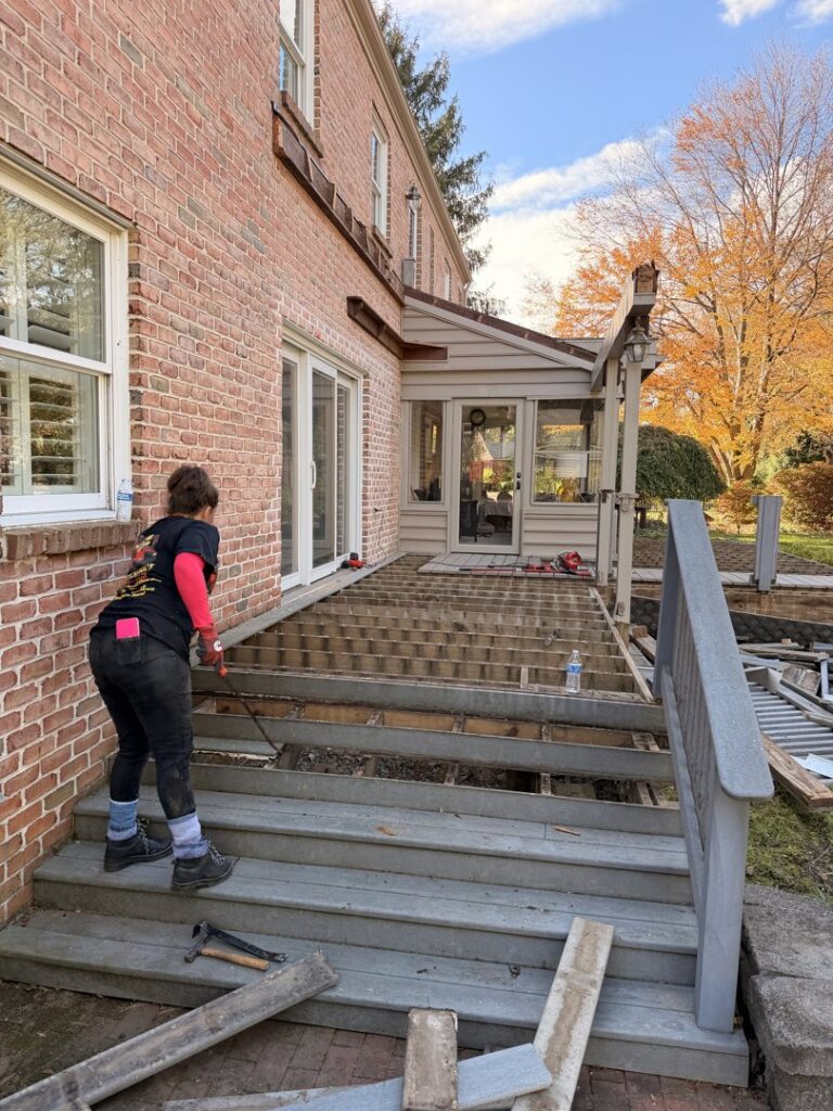 A worker removing debris from a partially demolished deck, showcasing a general junk removal job by Just Junk It in Lancaster, PA.
