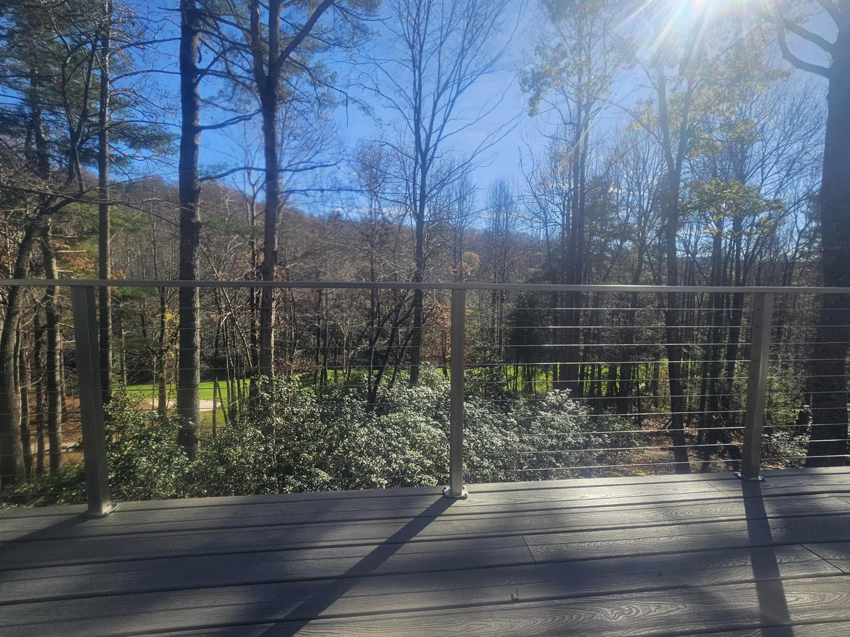 A deck with cable railing offering a beautiful forest view by American Cable & Rigging in Mills River, NC.