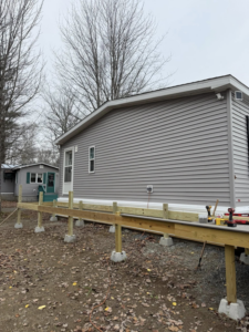 A wooden deck frame under construction next to a house, showcasing work in progress by The Finish Group in Bangor, ME.