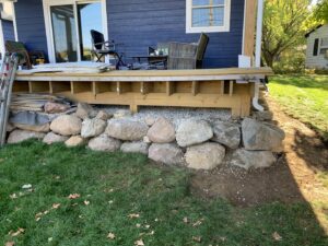 Deck framing under construction with decorative rocks at the base by S-Squared Construction in Madison, WI.