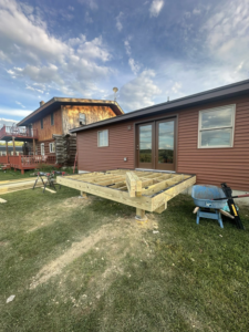 Wooden deck framing under construction next to a house by Next Generation Carpentry LLC in Bennington, VT.