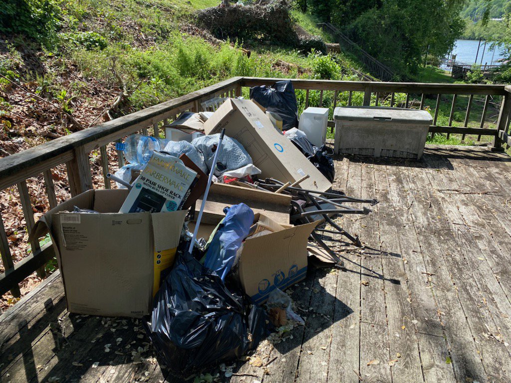 A pile of boxes, bags, and various household items cluttering a wooden deck, ready for junk removal by Trash Monkey Junk Removal in Charleston, WV.