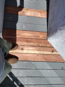 Close-up of an outdoor deck showing new wooden planks installed amidst older ones, illustrating deck repair by Handyman SanDiego in San Diego, CA.