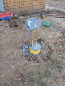 A sturdy deck post installed with concrete and hardware, part of a construction project by T&K Services in Idaho Falls, ID