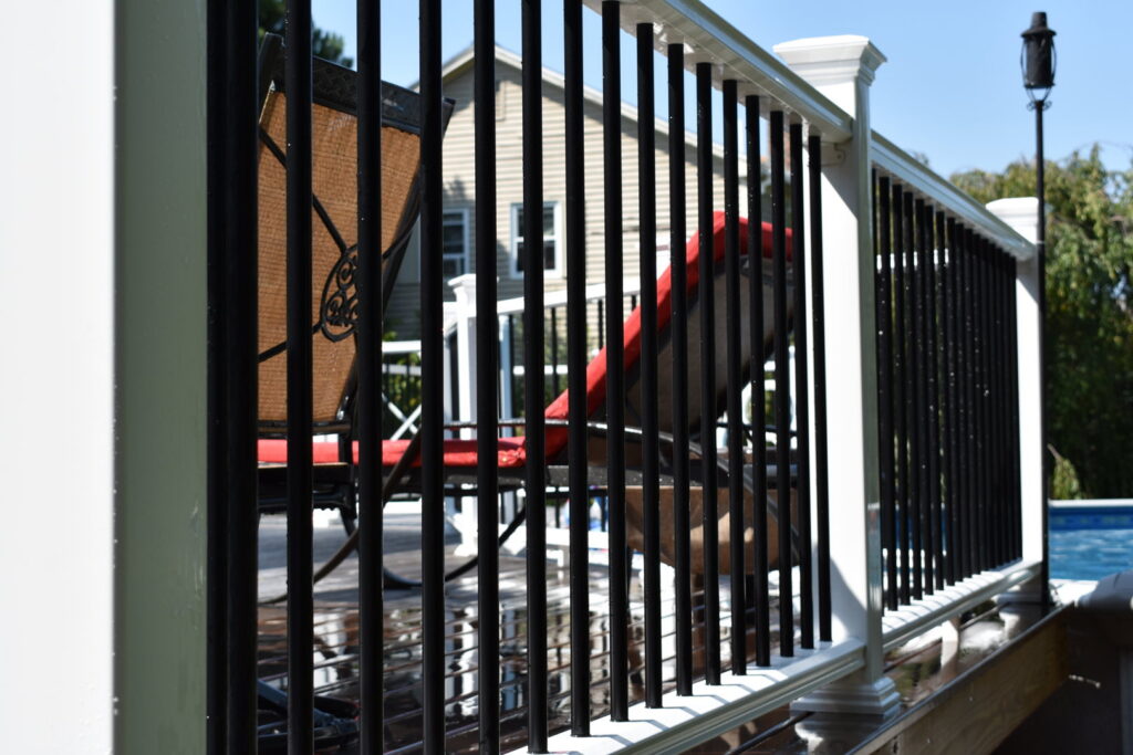A close-up of a newly installed deck railing with white posts and black balusters by Casco Bay Construction Services, LLC in South Portland, ME.