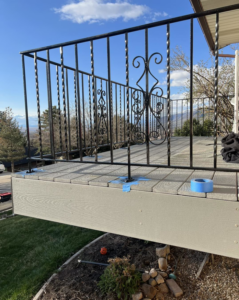 A black metal deck railing with painter's tape, indicating installation or painting work by Titan Handyman Services in Lewes, DE